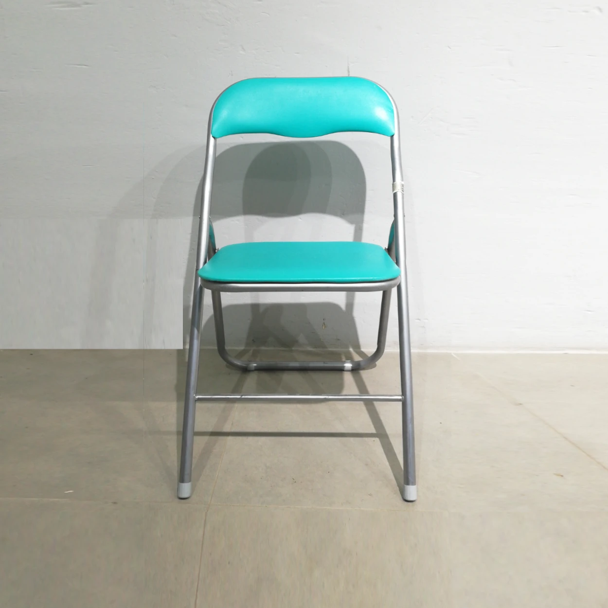 Cadira plegable amb entapissat verd (44x39x79cm) procedent d'una empresa en tancament